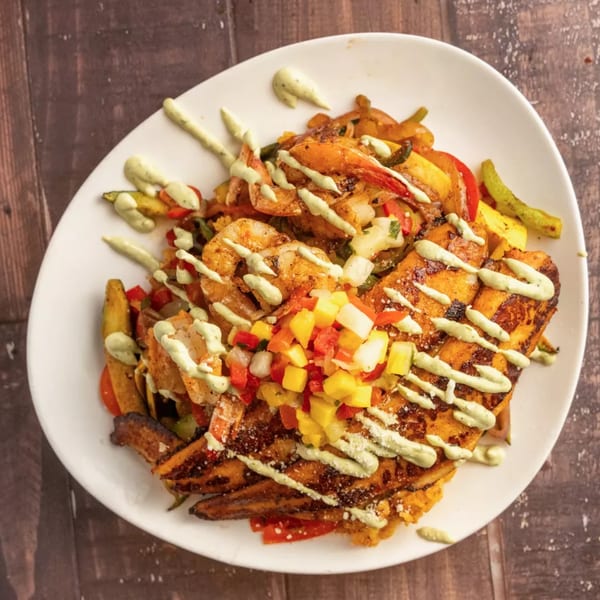 Grilled chicken and shrimp with colorful peppers, mango salsa, and a creamy green sauce.